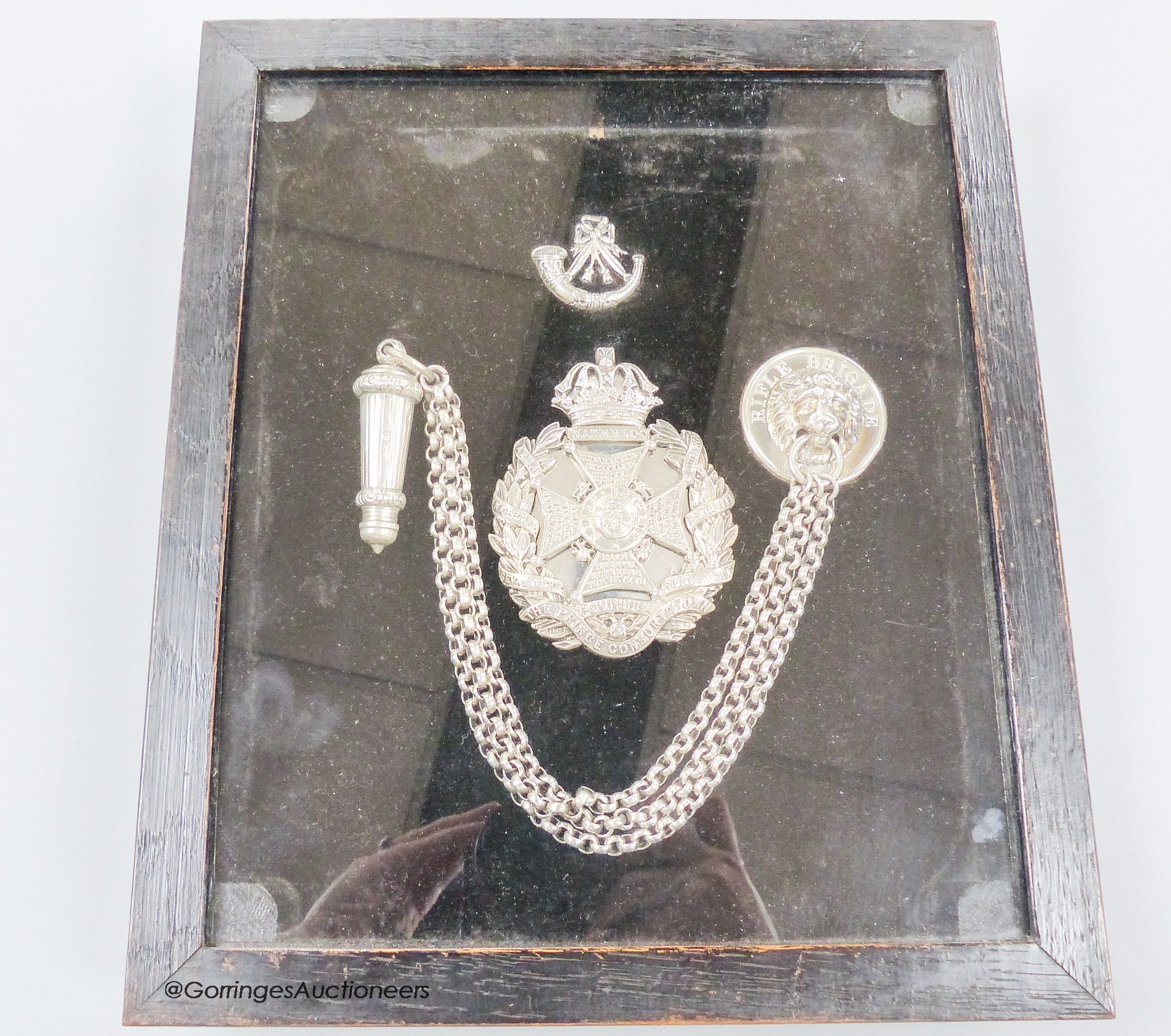 A framed late Victorian silver Rifle Brigade whistle and belt chain and two silver badges